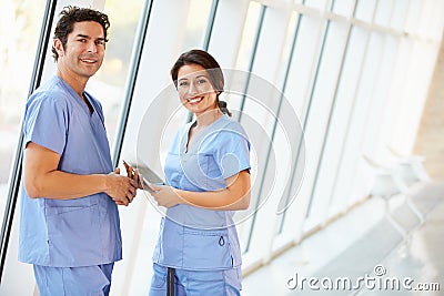 Medical Staff Talking In Hospital Corridor With Digital Tablet