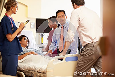 Medical Team Meeting Around Female Patient In Hospital Room