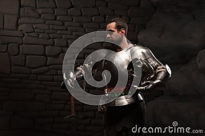 Medieval Knight posing with sword in a dark stone