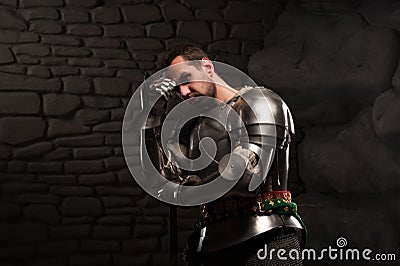 Medieval Knight posing with sword in a dark stone