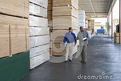 Men With Clipboards Walking Along Stacks Of Wood