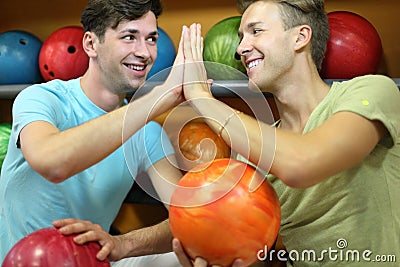 Men sit near shelves with balls in bowling club