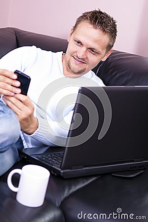 Men sofa with phone and computer use.