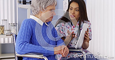 Mexican caregiver talking with tablet with senior patient