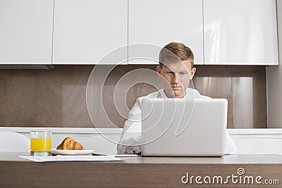 Mid adult businessman using laptop at breakfast table