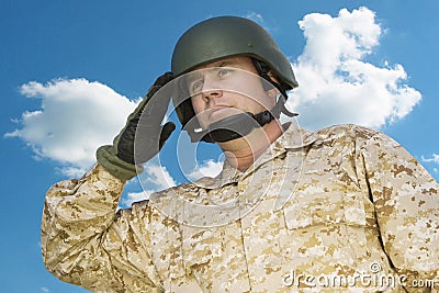 Mid-adult soldier in military uniform saluting against cloudy sky