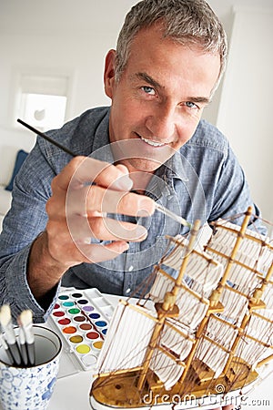Mid age man painting a model ship at home