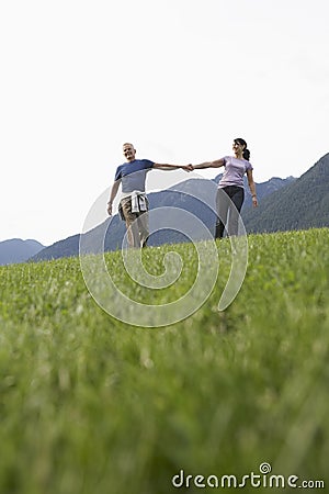 Middle Aged Couple Holding Hands On Meadow