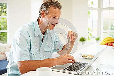 Middle Aged Man Using Laptop Over Breakfast