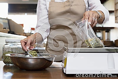 Midsection of an employee measuring ingredient on weight scale in spice store