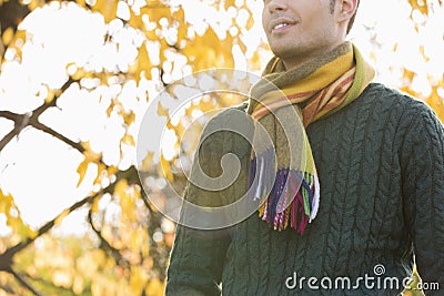 Midsection of man wearing sweater and muffler in park during autumn