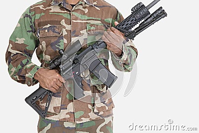 Midsection of US Marine Corps soldier holding M4 assault rifle over gray background