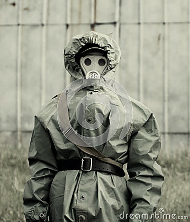 Military man in protective suit and gas mask outdoors