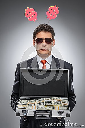 Millionaire. Confident man in formal wear holding a suitcase ful