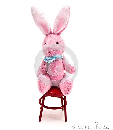  toy bunny rabbit sitting on a red metal chair on a white background