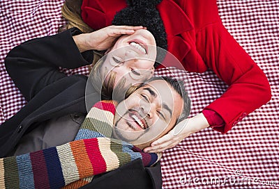 Mixed Race Couple Wearing Winter Clothing on Picnic Blanket in a Park