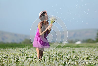 Model in a pink dress on a dandelion field in a straw hat