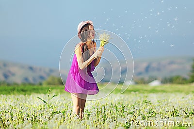 Model in a pink dress on a dandelion field in a straw hat