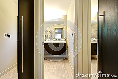 Modern bathroom with closet doors and hallway with mirrors.