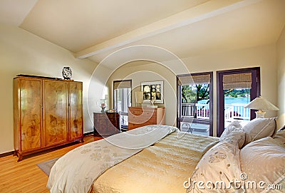 Modern luxury bedroom with bed, dresser and lake view.