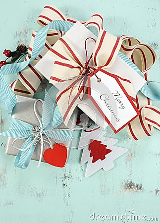 Modern red and white Christmas decorations on aqua blue wood background, with white gift closeup - vertical.