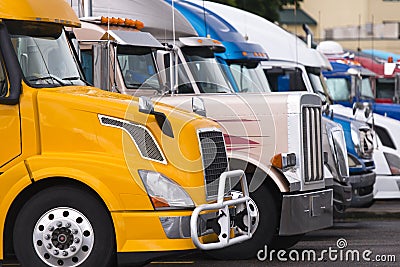 Modern yellow semi truck on foreground of other trucks