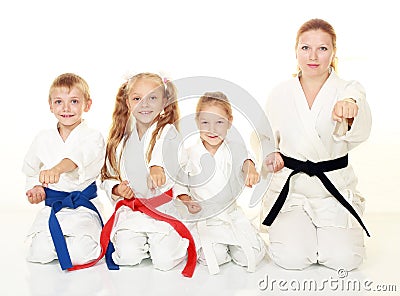 Mom with her daughter and a boy sitting with his sister in a ritual pose karate and beat his fist