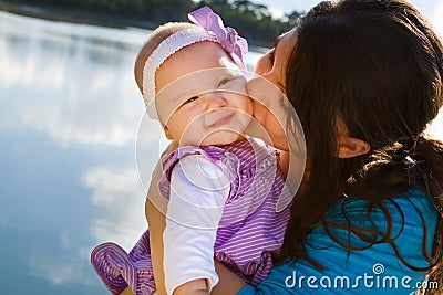 Mom Kissing Baby Daughter By Lake