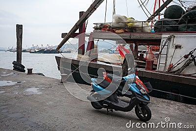 Moped and fishing boat in the fishing port in Macau.