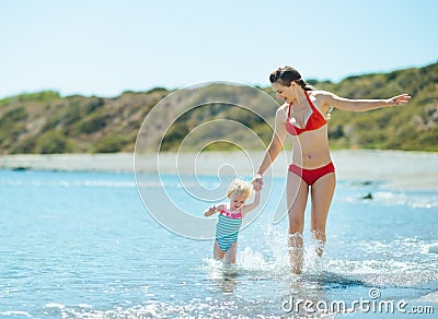 Mother and baby girl running on sea coast
