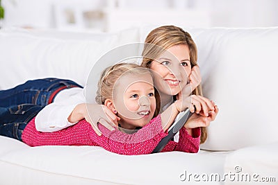 Mother and daugher lying on sofa watching tv