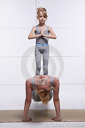 Mother and daughter doing yoga exercise, fitness, gym wearing the same comfortable tracksuits family sports paired woman p