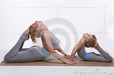 Mother daughter doing yoga exercise, fitness, gym wearing the same comfortable tracksuits, family sports, sports paired