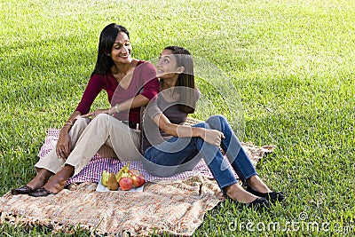 Mother and daughter sitting on picnic blanket