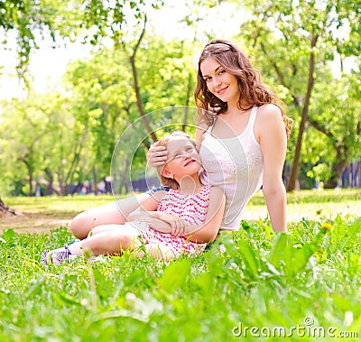 Mother and daughter sitting together on the grass