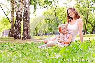 Mother and daughter sitting together on the grass