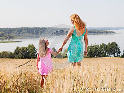 Mother and daughter walking in summer field