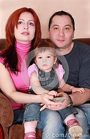 Mother, father and daughter sitting and watch TV