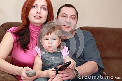 Mother, father and daughter sitting and watch TV