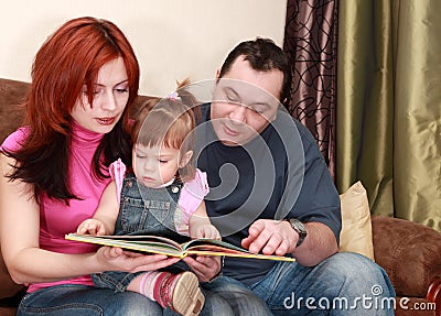 Mother, father and little daughter reads book