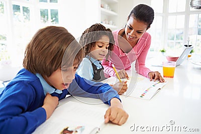 Mother Helping Children With Homework In Kitchen