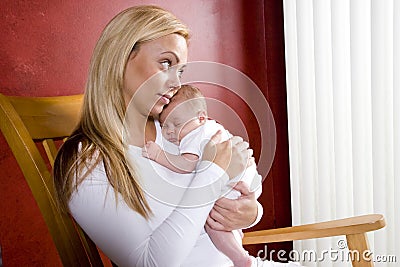 Mother holding newborn baby in rocking chair