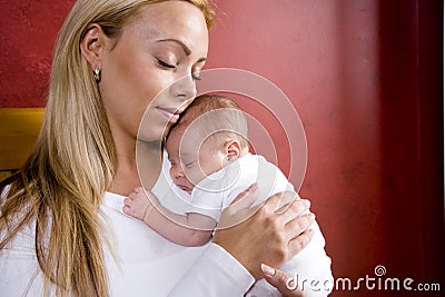 Mother holding newborn baby in rocking chair
