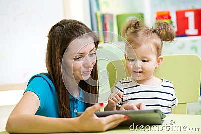 Mother and kid are looking to play and read tablet computer
