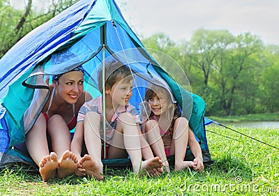 Mother and kids in swimsuit sit in tent