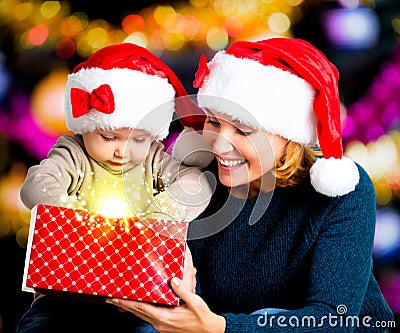 Mother with little child opens the box with gifts on christmas