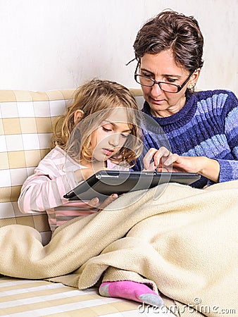 Mother and little daughter using tablet device