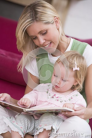 Mother in living room reading book with baby