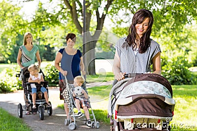 Mother Looking At Baby In Stroller At Park