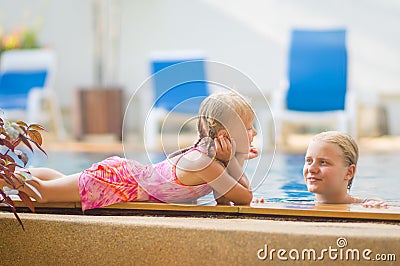 Mother in pool and daughter on pool side have fun and talk in tr